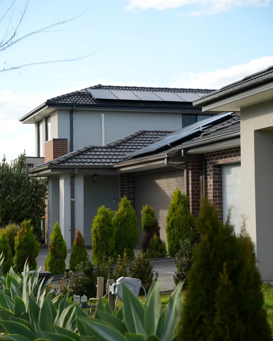 Two homes with solar panels on their roofs, behind a front garden